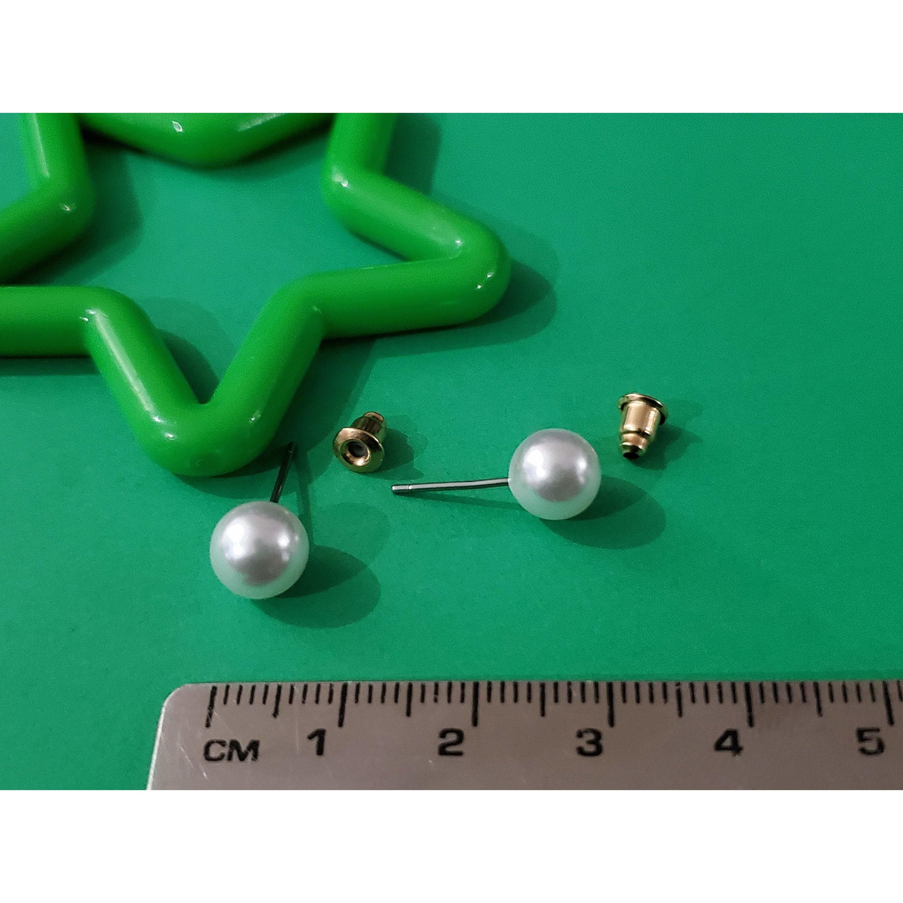 Elegant white imitation pearl studs displayed on a soft background, showcasing their lustrous finish and classic design.