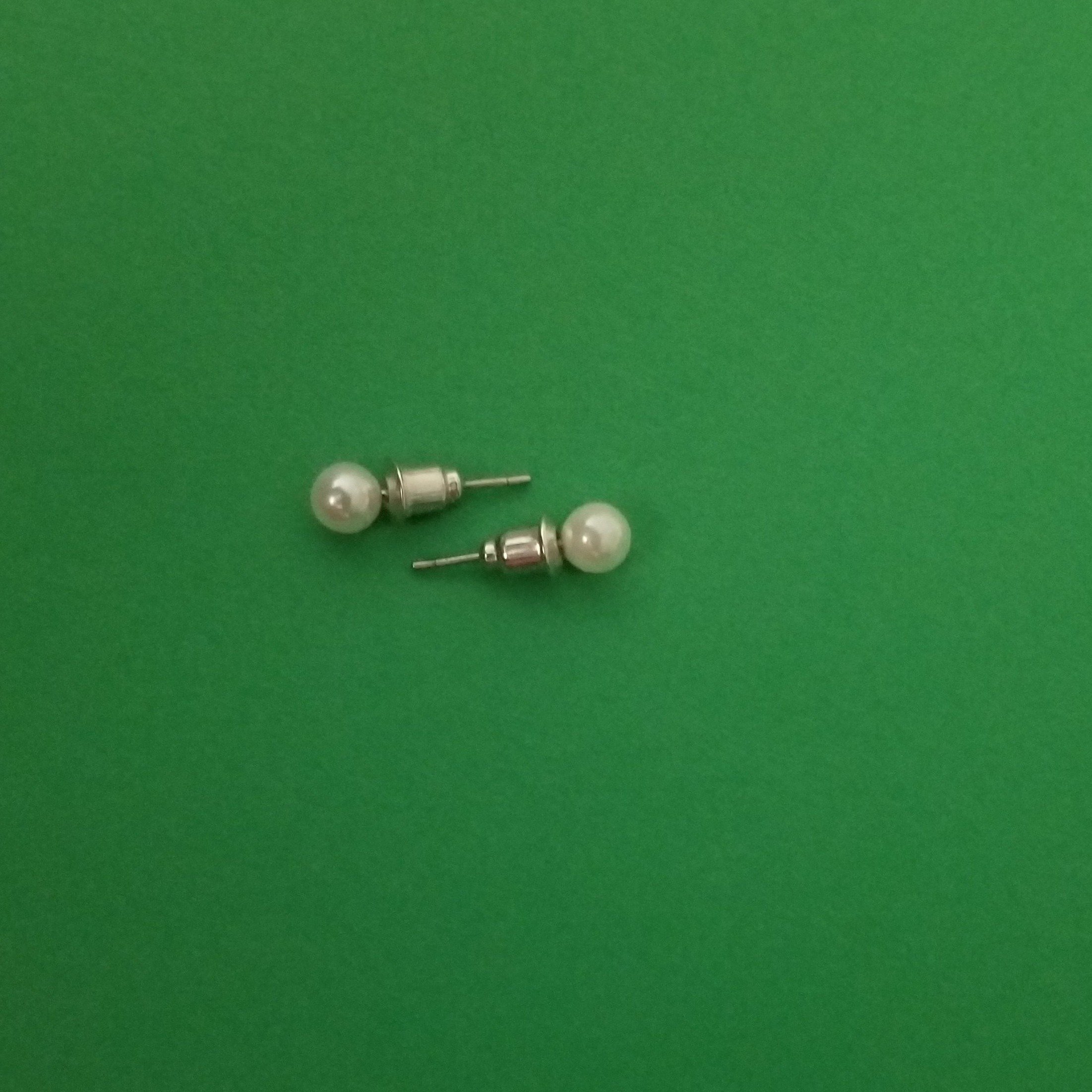 Elegant white imitation pearl studs displayed on a soft background, showcasing their lustrous finish and classic design.