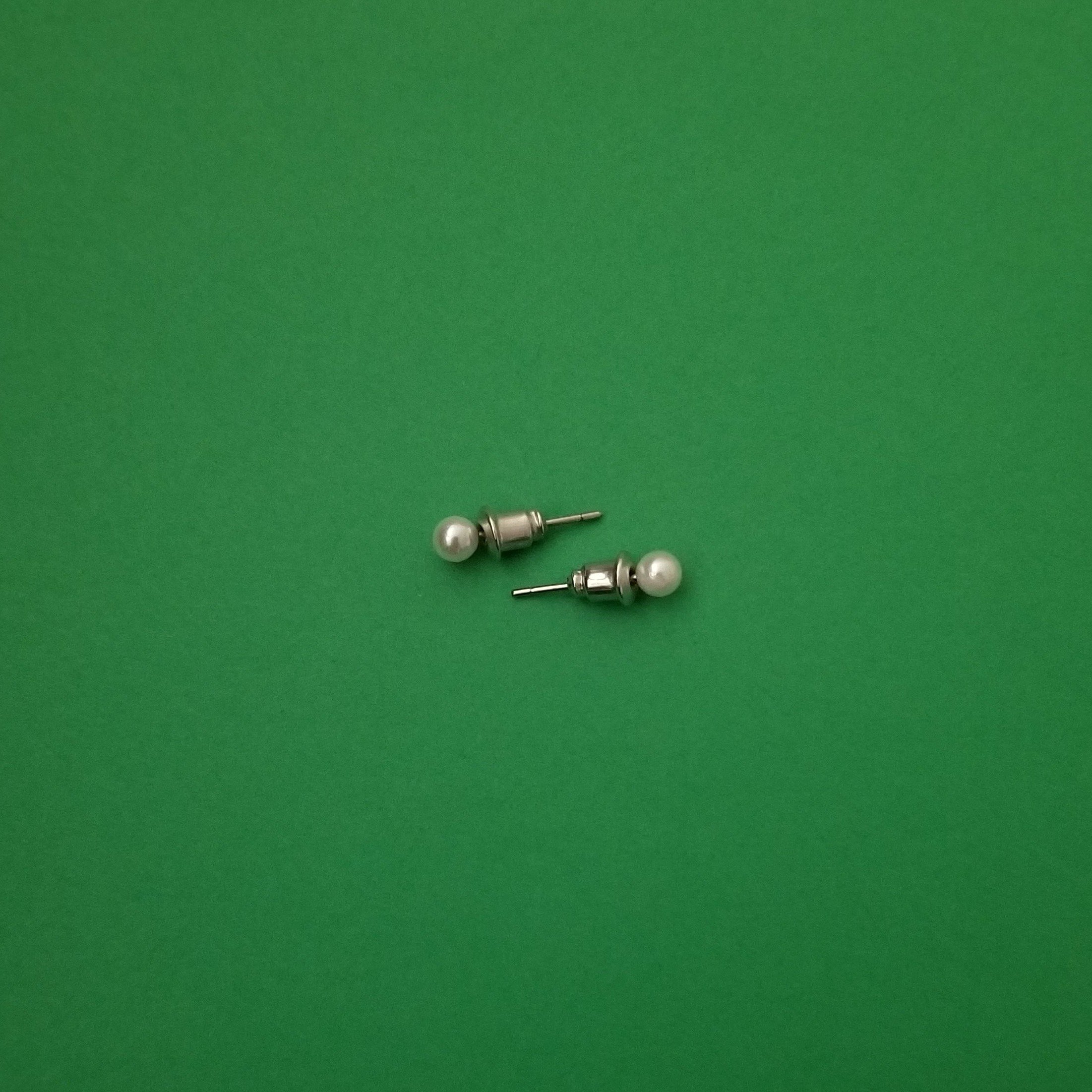 Elegant white imitation pearl studs displayed on a soft background, showcasing their lustrous finish and classic design.