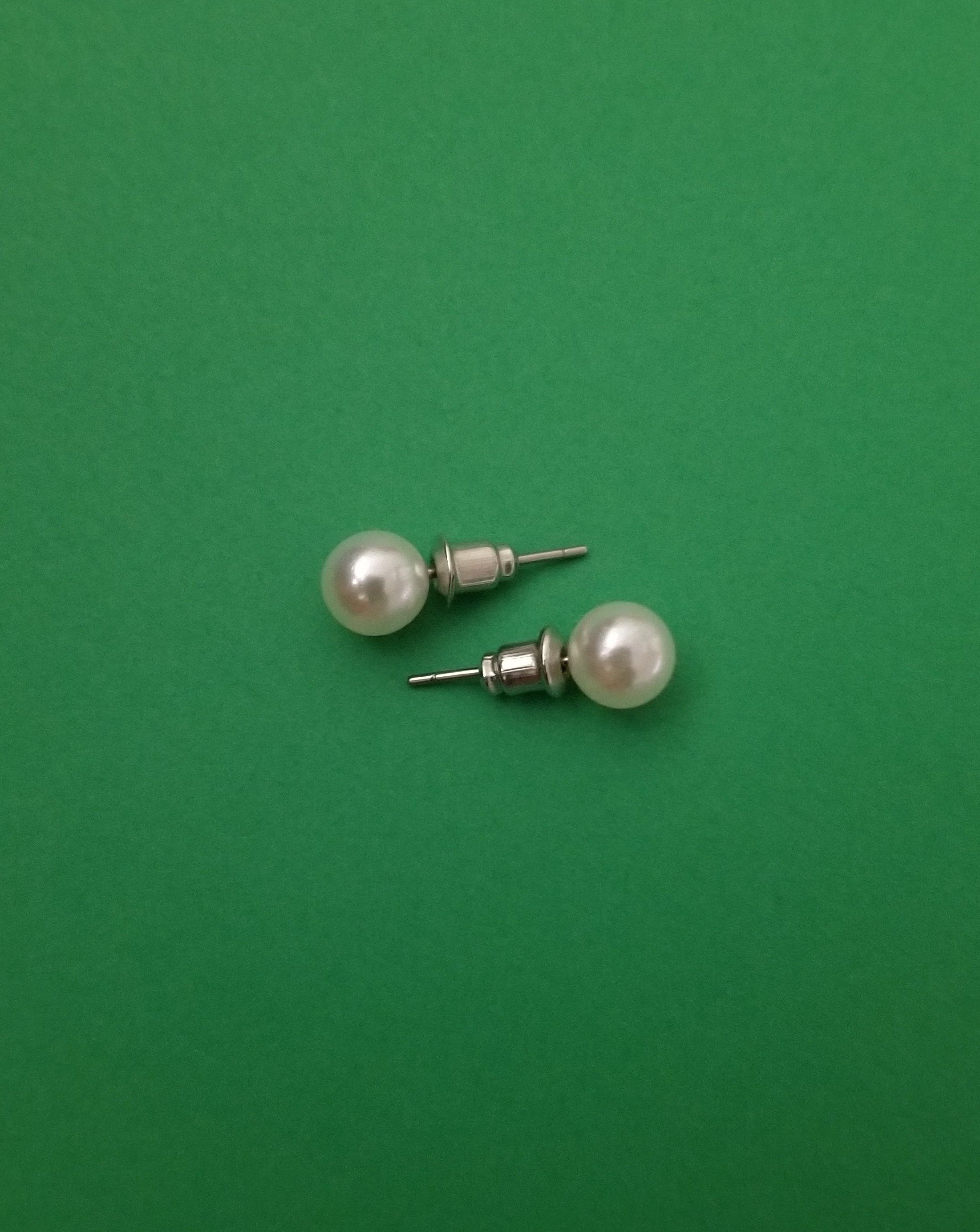 Elegant white imitation pearl studs displayed on a soft background, showcasing their lustrous finish and classic design.