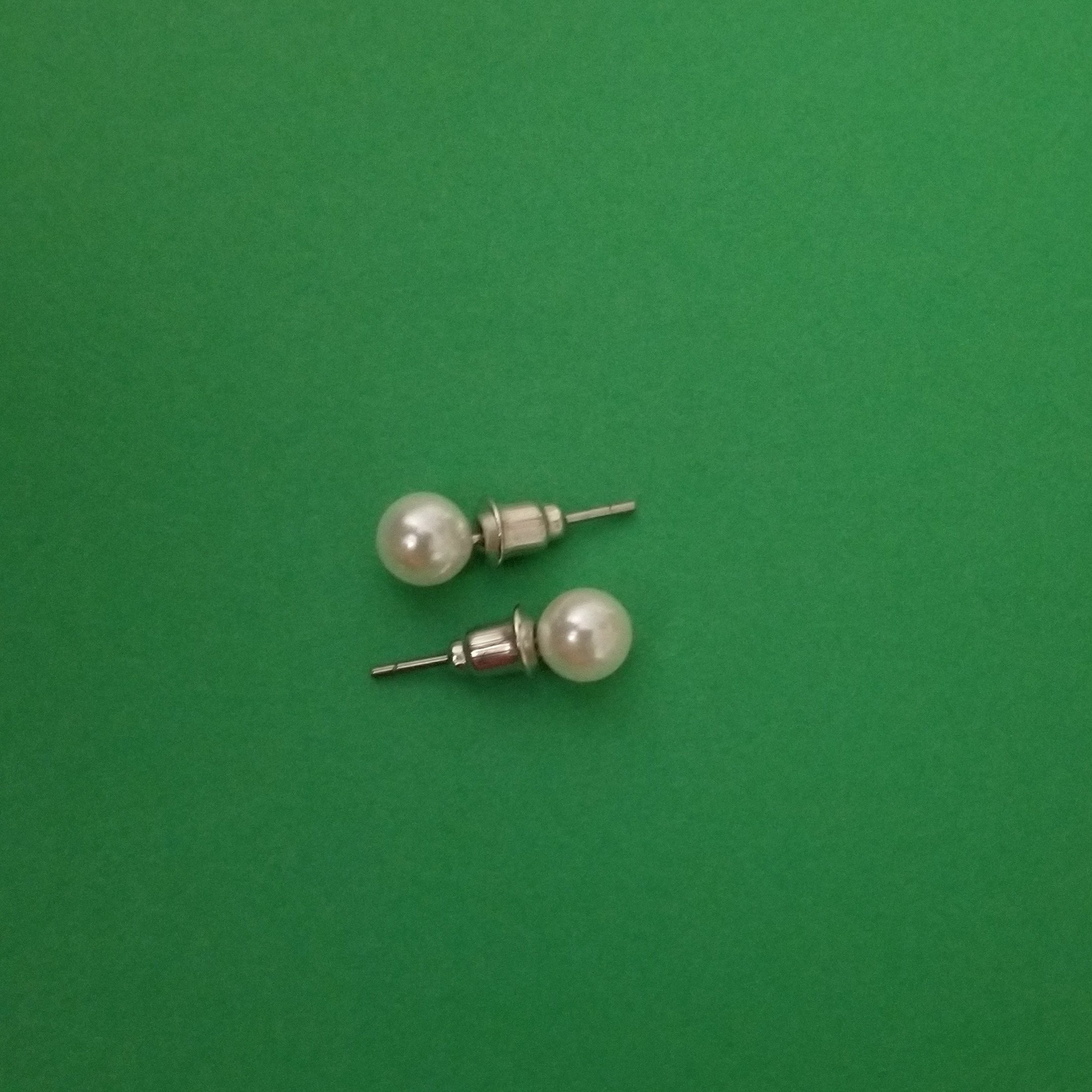 Elegant white imitation pearl studs displayed on a soft background, showcasing their lustrous finish and classic design.