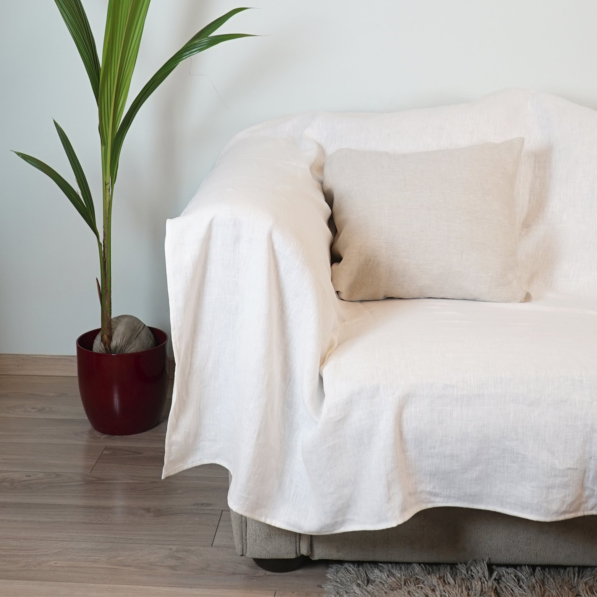 Elegant white linen couch cover draped over a stylish sofa, showcasing its soft texture and natural elegance in a cozy living room setting.