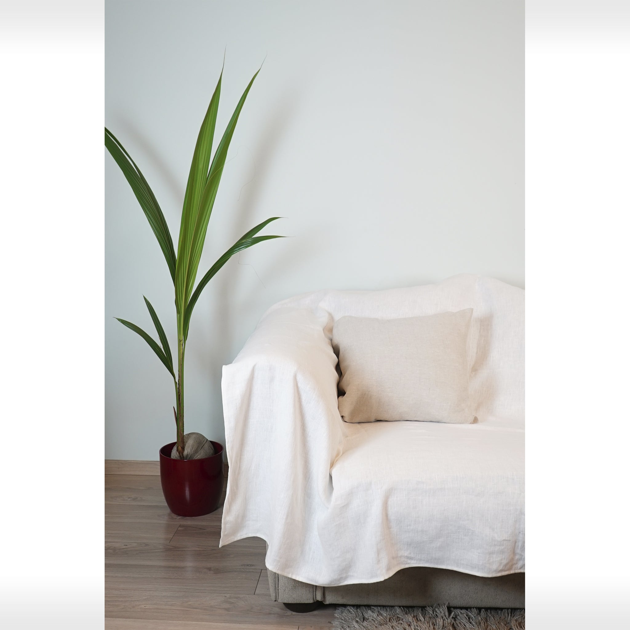 Elegant white linen couch cover draped over a stylish sofa, showcasing its soft texture and natural elegance in a cozy living room setting.