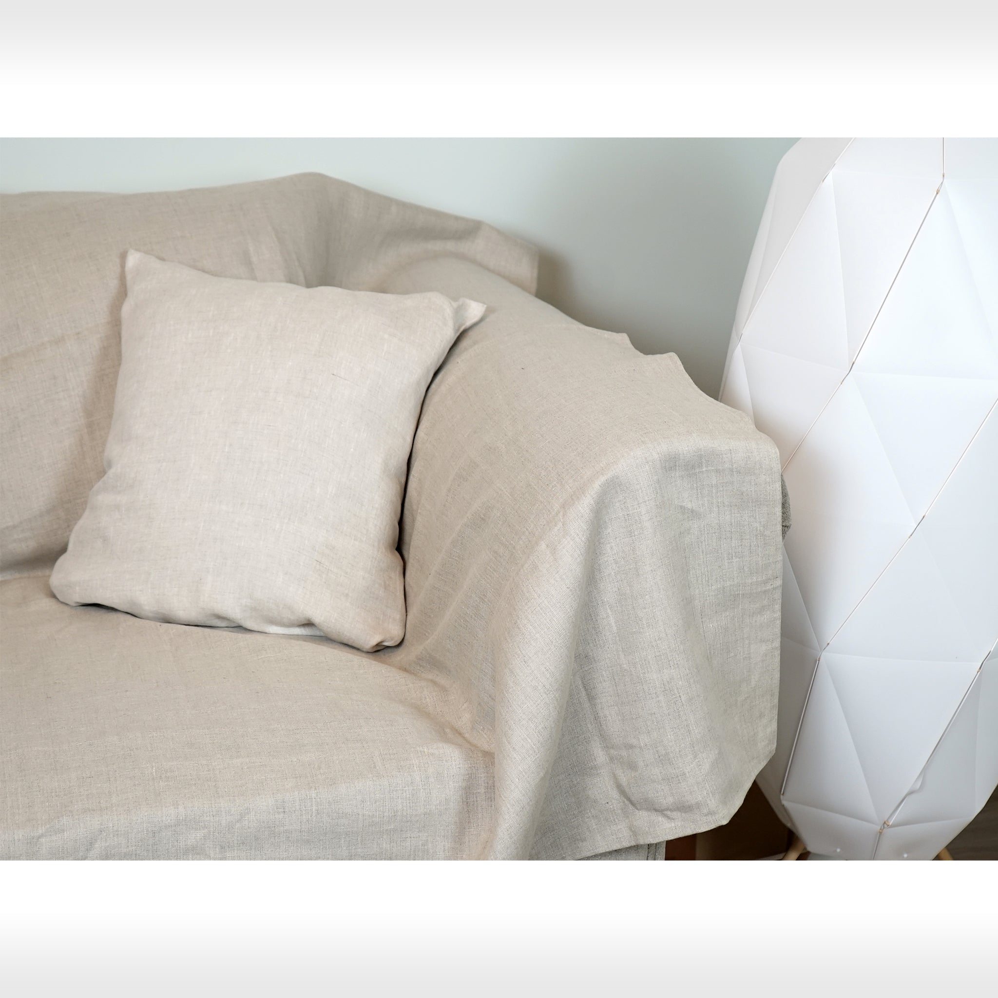 Elegant white linen couch cover draped over a stylish sofa, showcasing its soft texture and natural elegance in a cozy living room setting.