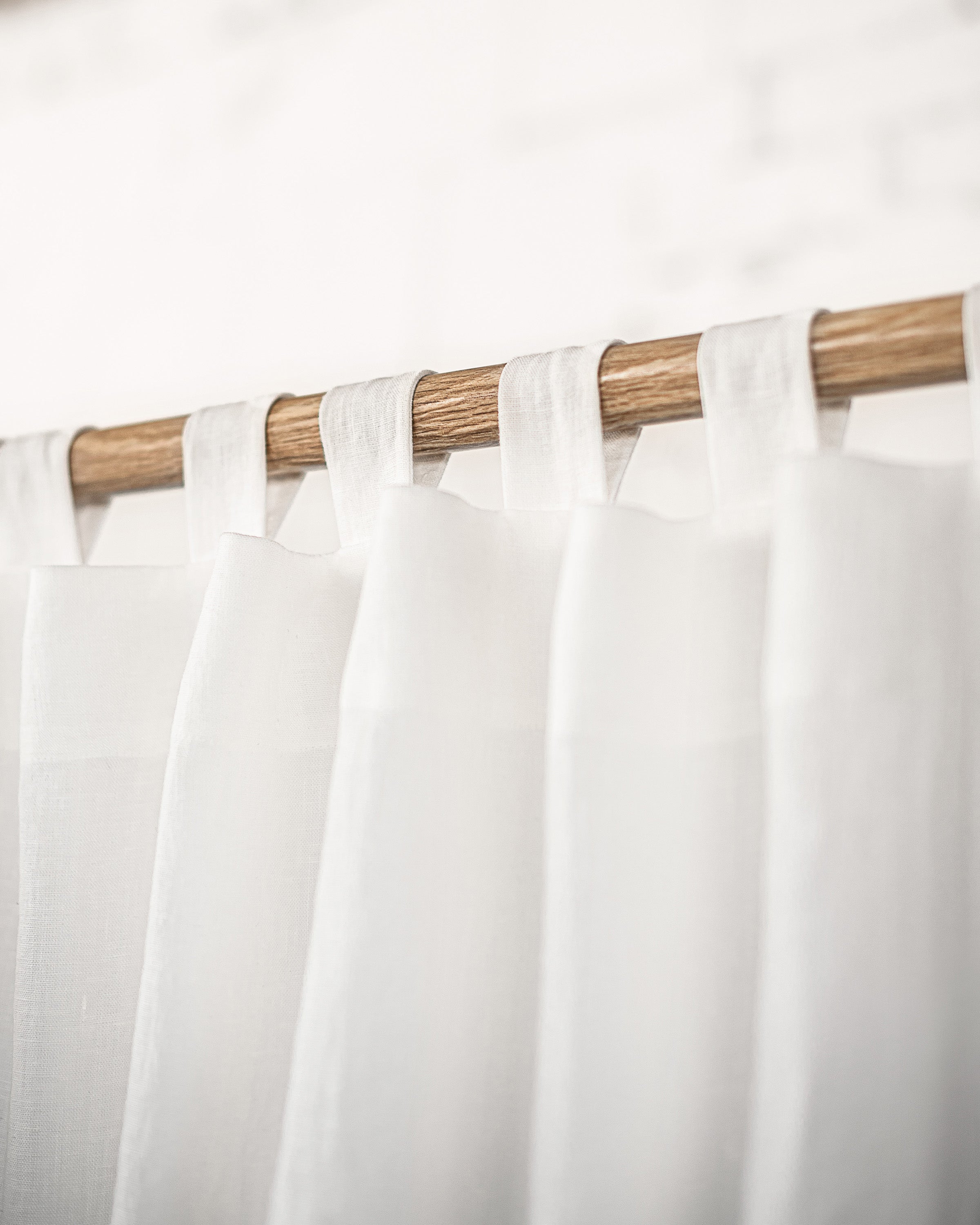 Elegant white linen curtain with tab tops, showcasing a semi-sheer texture and soft draping, perfect for enhancing home decor.