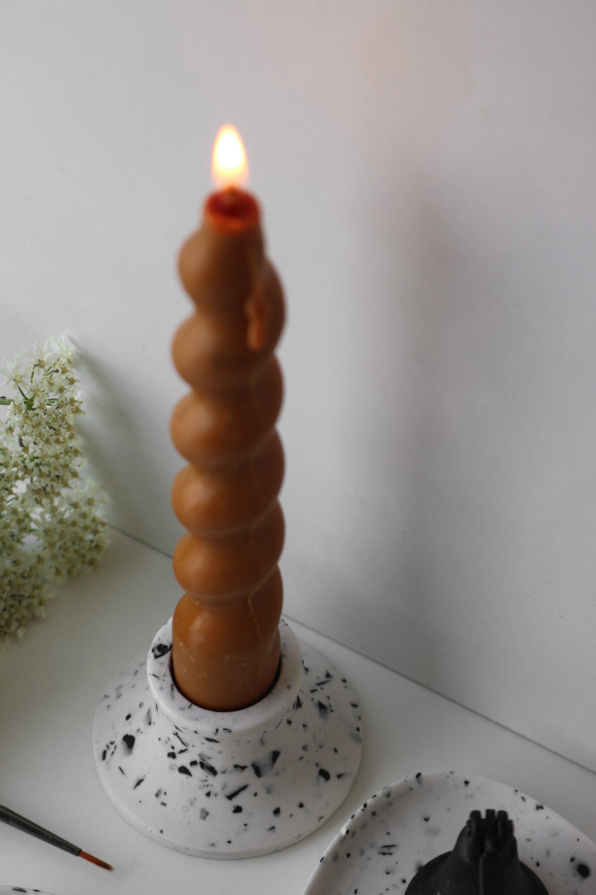 A stylish white and black terrazzo candle holder, showcasing unique patterns and a sleek design, perfect for home decor.