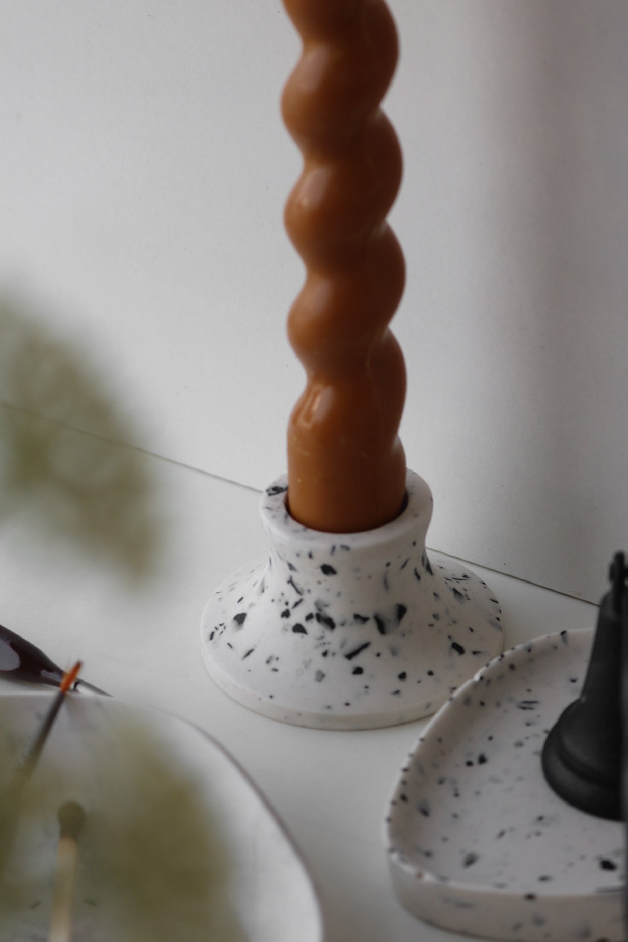 A stylish white and black terrazzo candle holder, showcasing unique patterns and a sleek design, perfect for home decor.