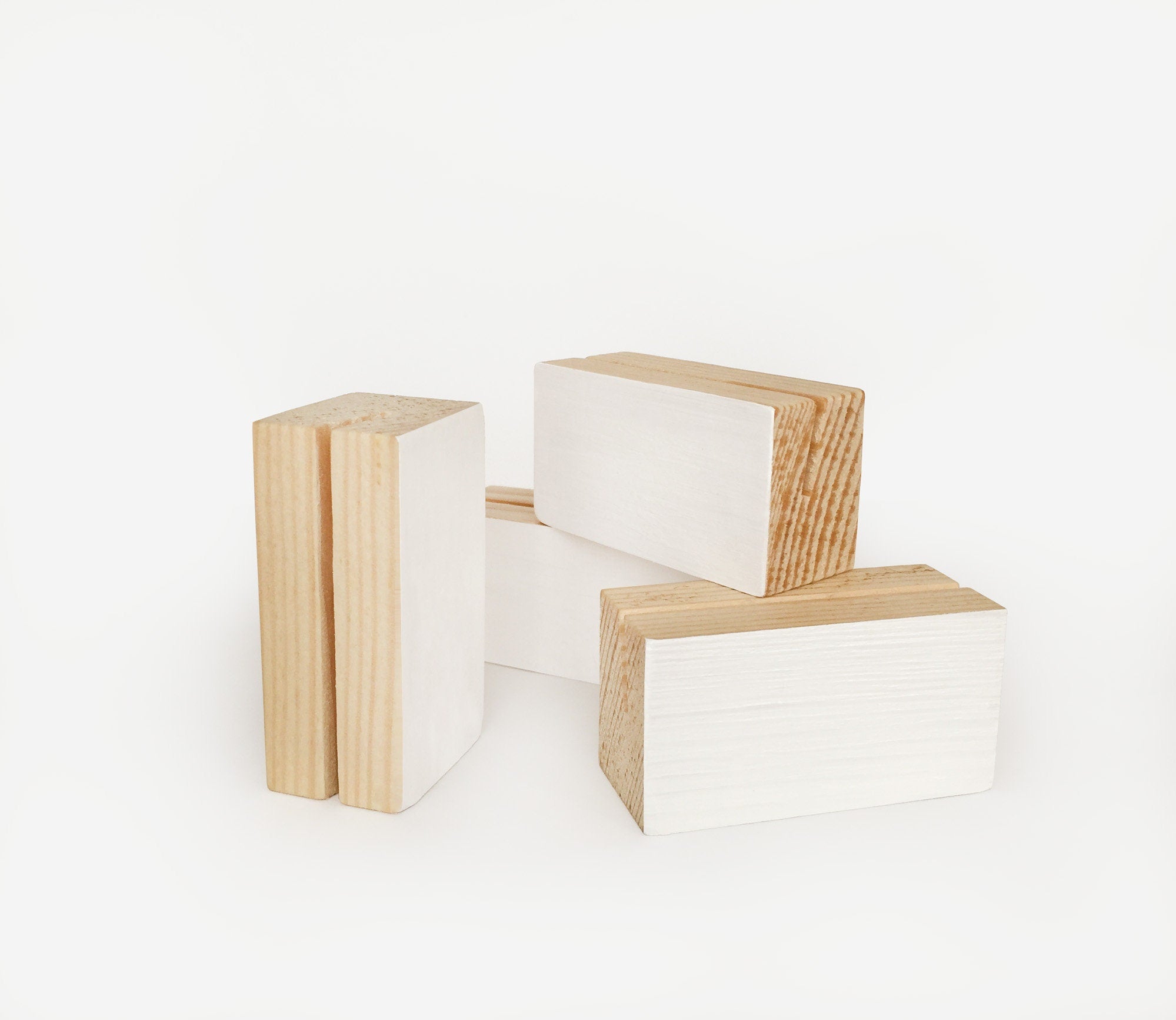 A white wood block holder displaying various small art prints and photos, showcasing its elegant design and eco-friendly craftsmanship.