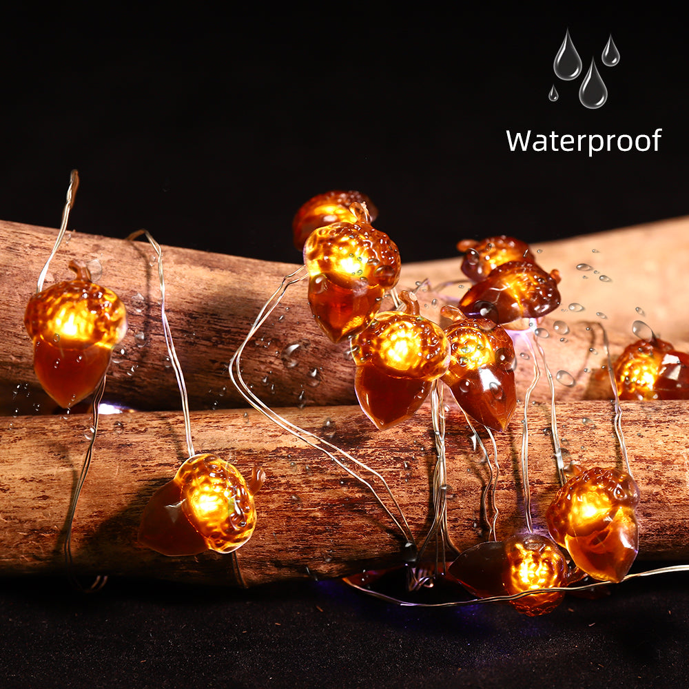 A string of battery-powered acorn-shaped LED lights, perfect for Thanksgiving and autumn decorations, showcasing a warm glow against a cozy backdrop.