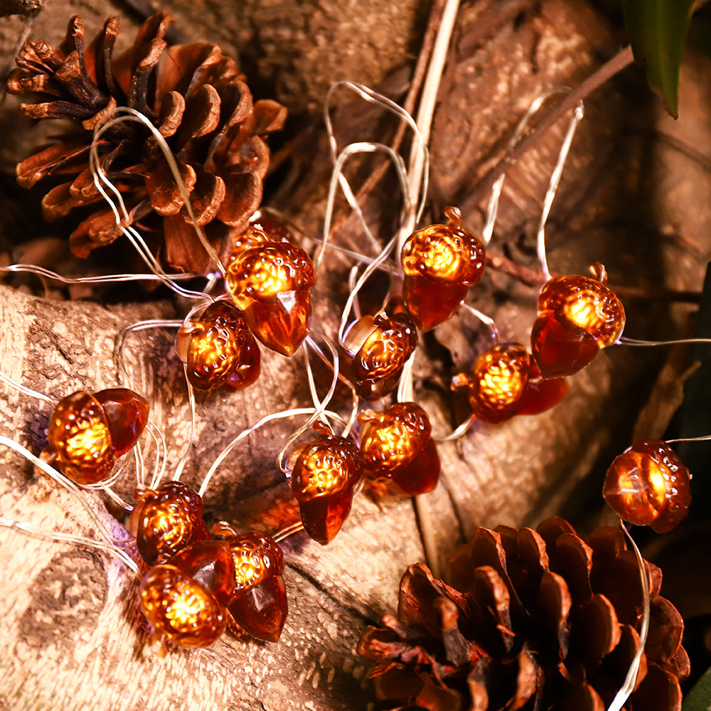 A string of battery-powered acorn-shaped LED lights, perfect for Thanksgiving and autumn decorations, showcasing a warm glow against a cozy backdrop.