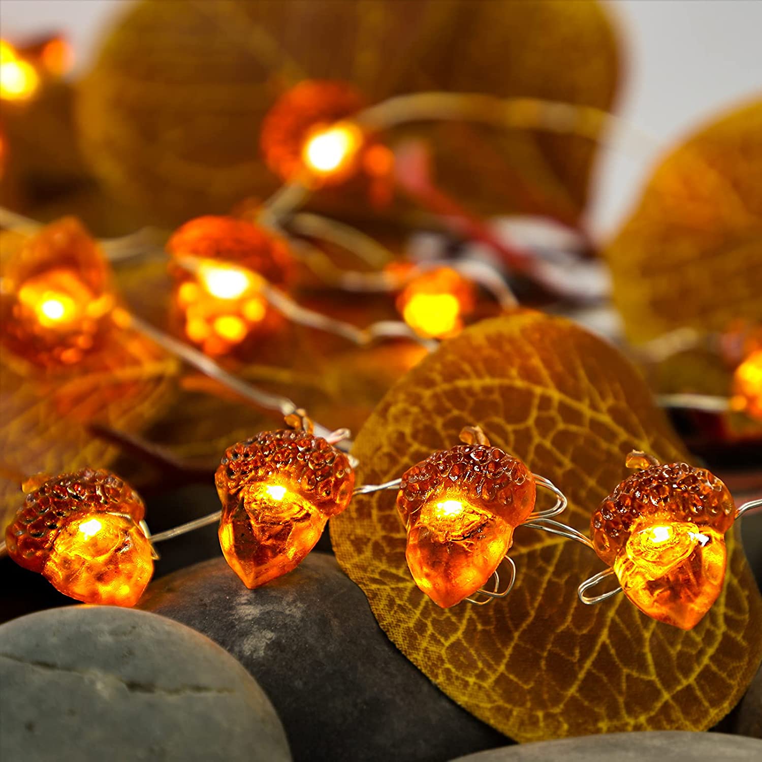 A string of battery-powered acorn-shaped LED lights, perfect for Thanksgiving and autumn decorations, showcasing a warm glow against a cozy backdrop.