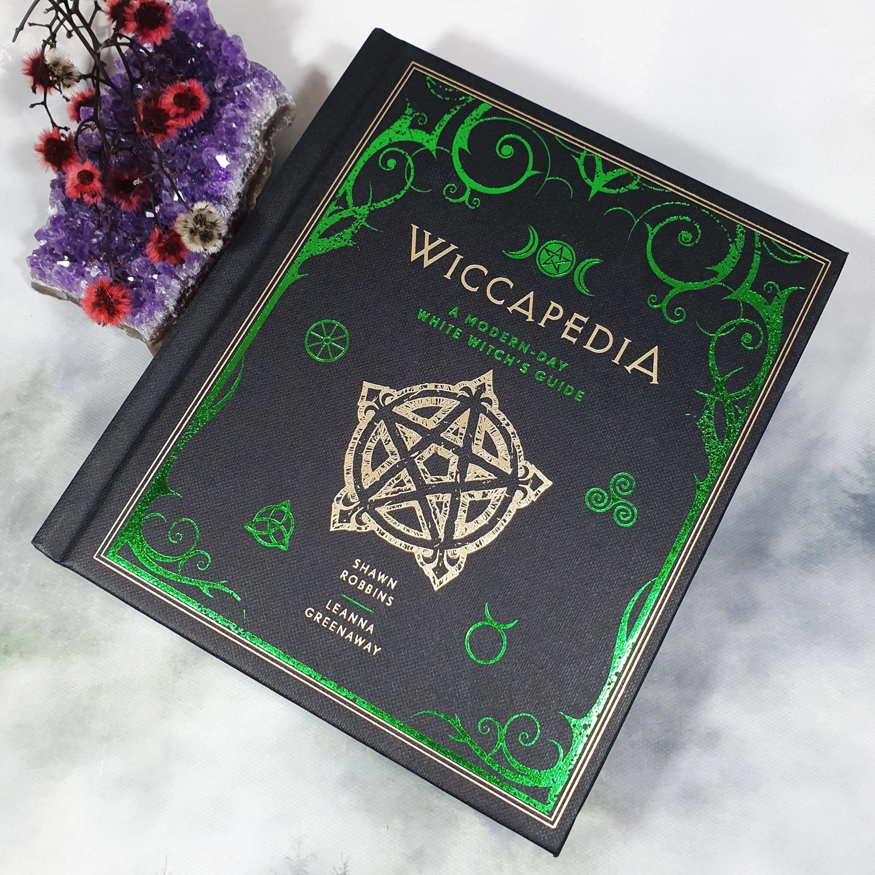 Cover of Wiccapedia, a modern guide for witches by Shawn Robbins and Leanna Greenaway, featuring mystical symbols and vibrant colors.