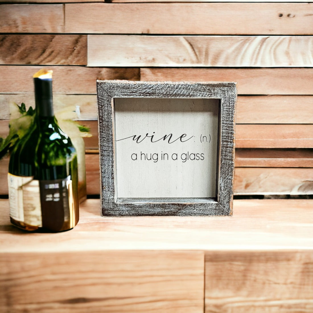 A beautifully framed wooden sign that reads 'Wine: A Hug', featuring a white-washed finish, perfect for home decor.