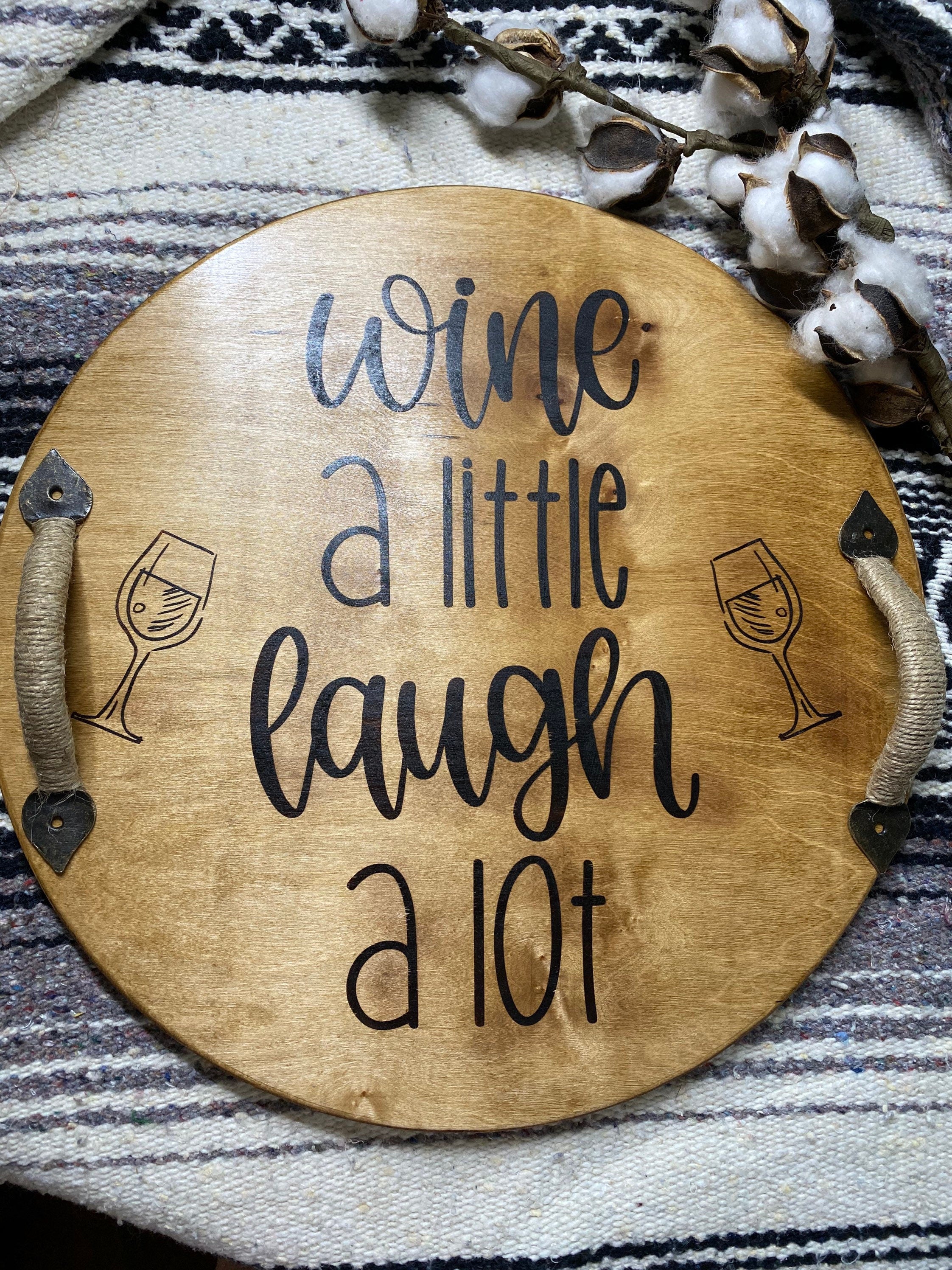 Rustic round wooden serving tray with twine wrapped metal handles and a burned sentiment, perfect for wine serving.