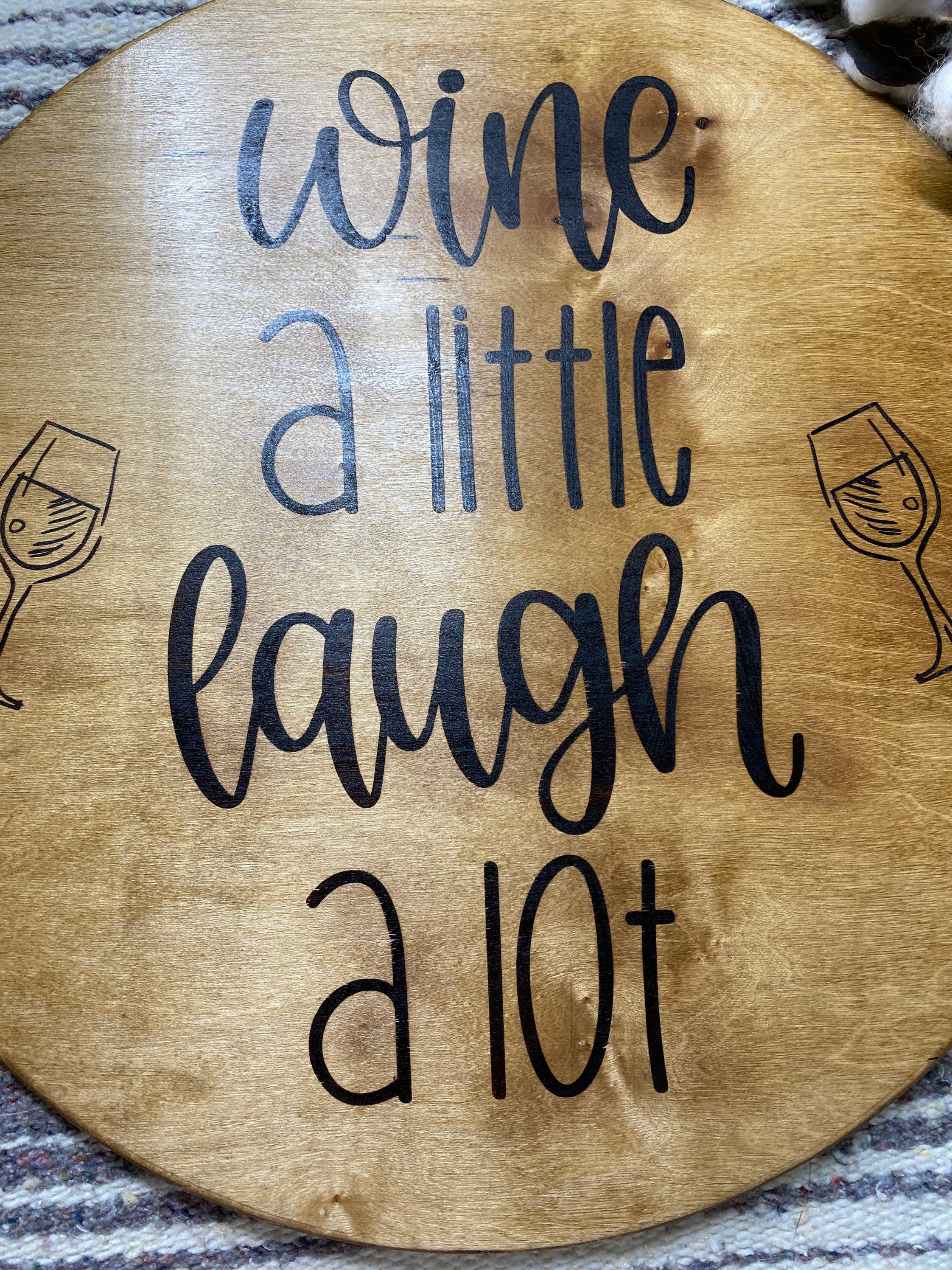 Rustic round wooden serving tray with twine wrapped metal handles and a burned sentiment, perfect for wine serving.