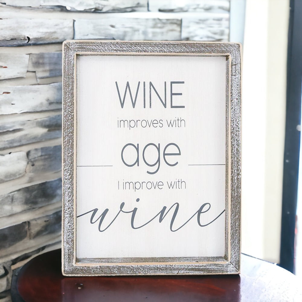 A stylish wood sign that reads 'Wine improves with age, I improve with wine', featuring a modern design in white and grey colors.