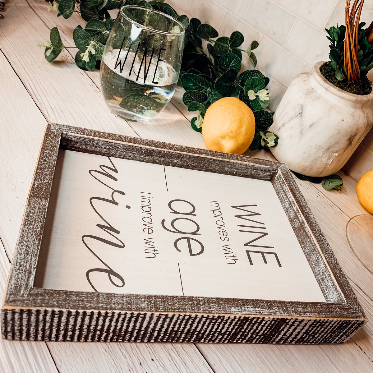 A stylish wood sign that reads 'Wine improves with age, I improve with wine', featuring a modern design in white and grey colors.