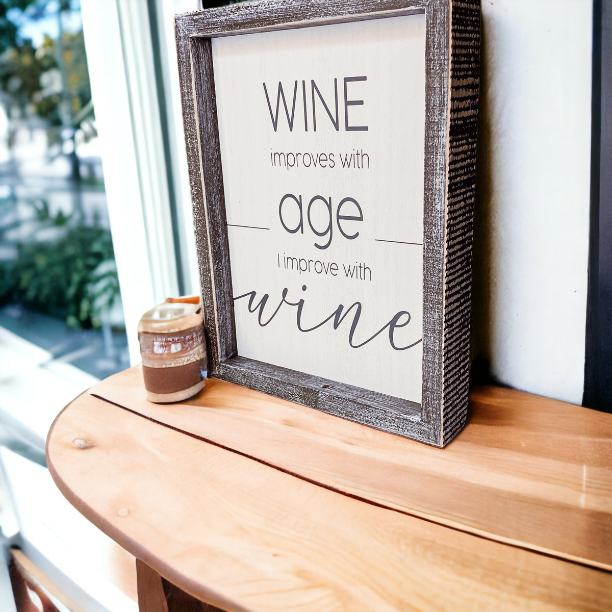 A stylish wood sign that reads 'Wine improves with age, I improve with wine', featuring a modern design in white and grey colors.