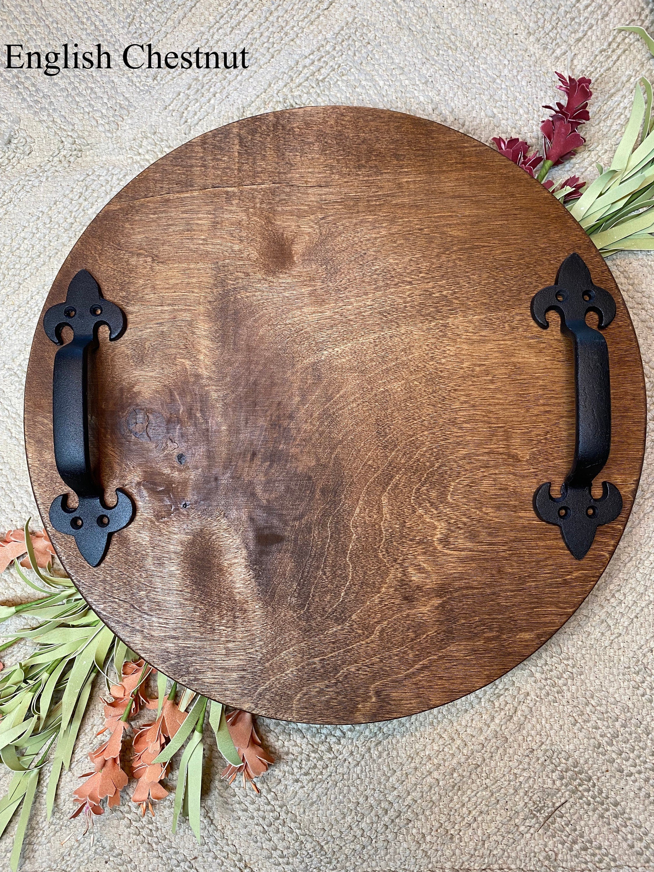 A rustic round wood serving tray made of birch plywood with black metal handles, showcasing a beautiful stain finish.