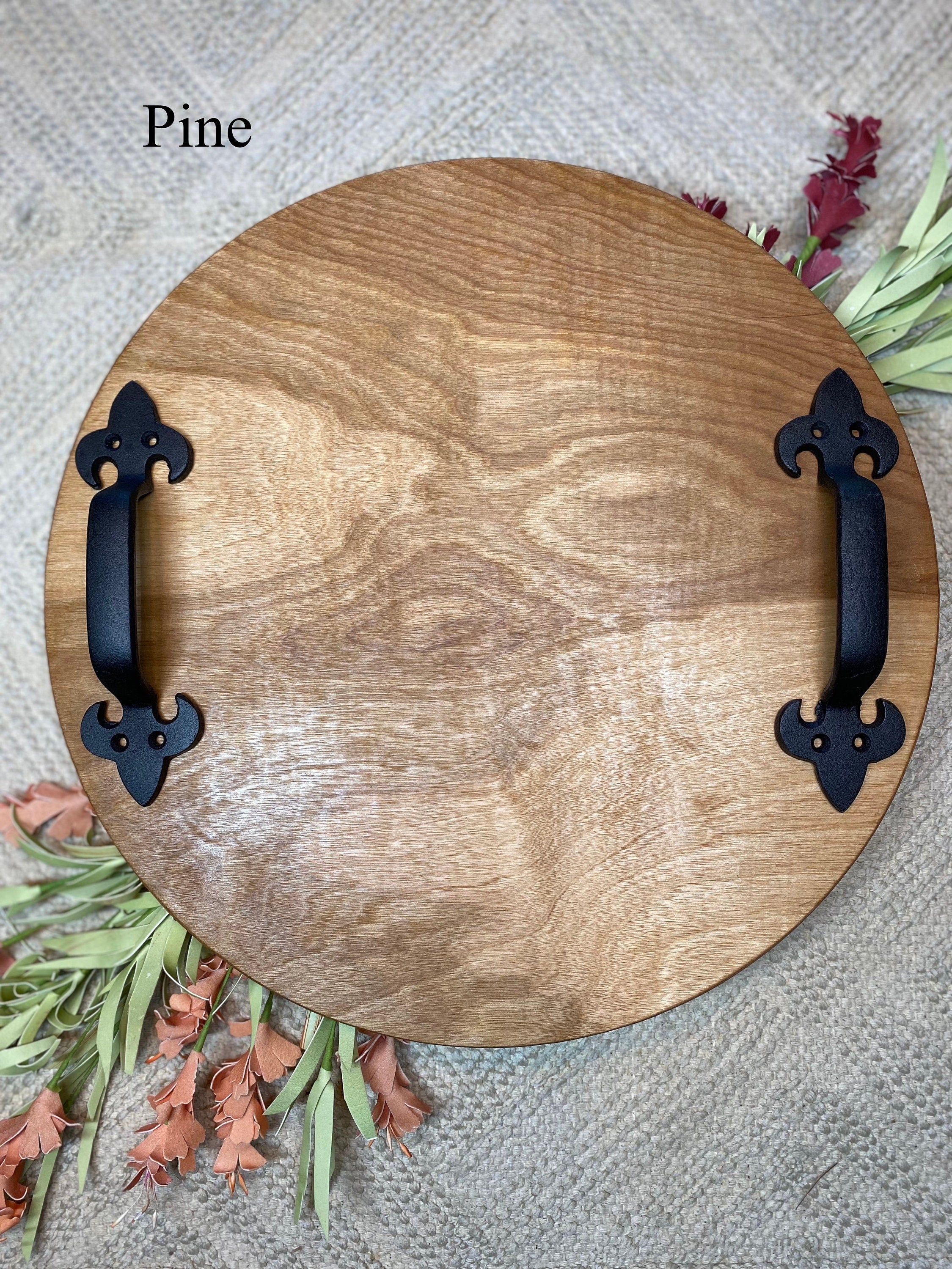 A rustic round wood serving tray made of birch plywood with black metal handles, showcasing a beautiful stain finish.