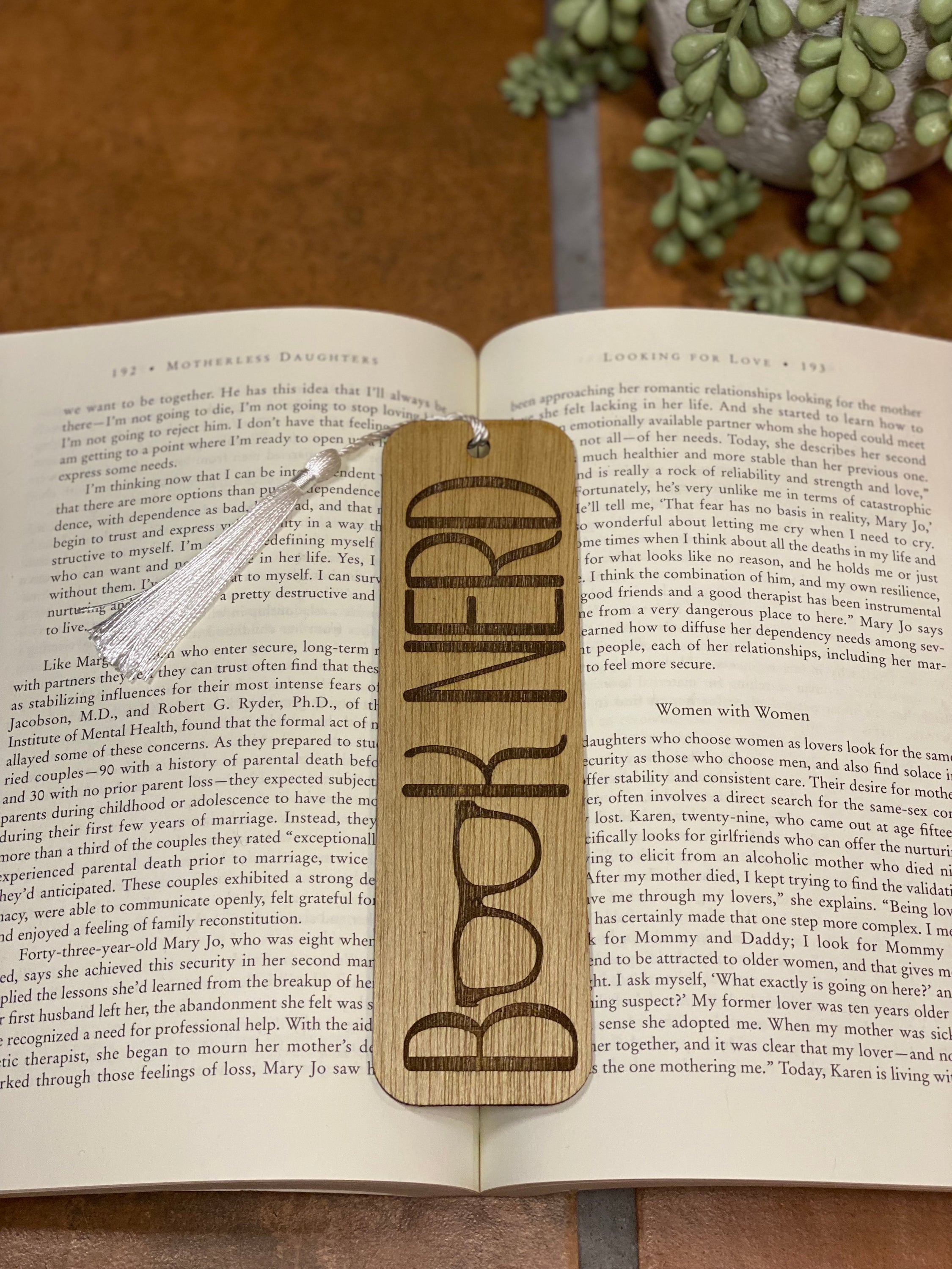 A beautifully crafted wooden bookmark with a white tassel, showcasing unique laser engraved designs.