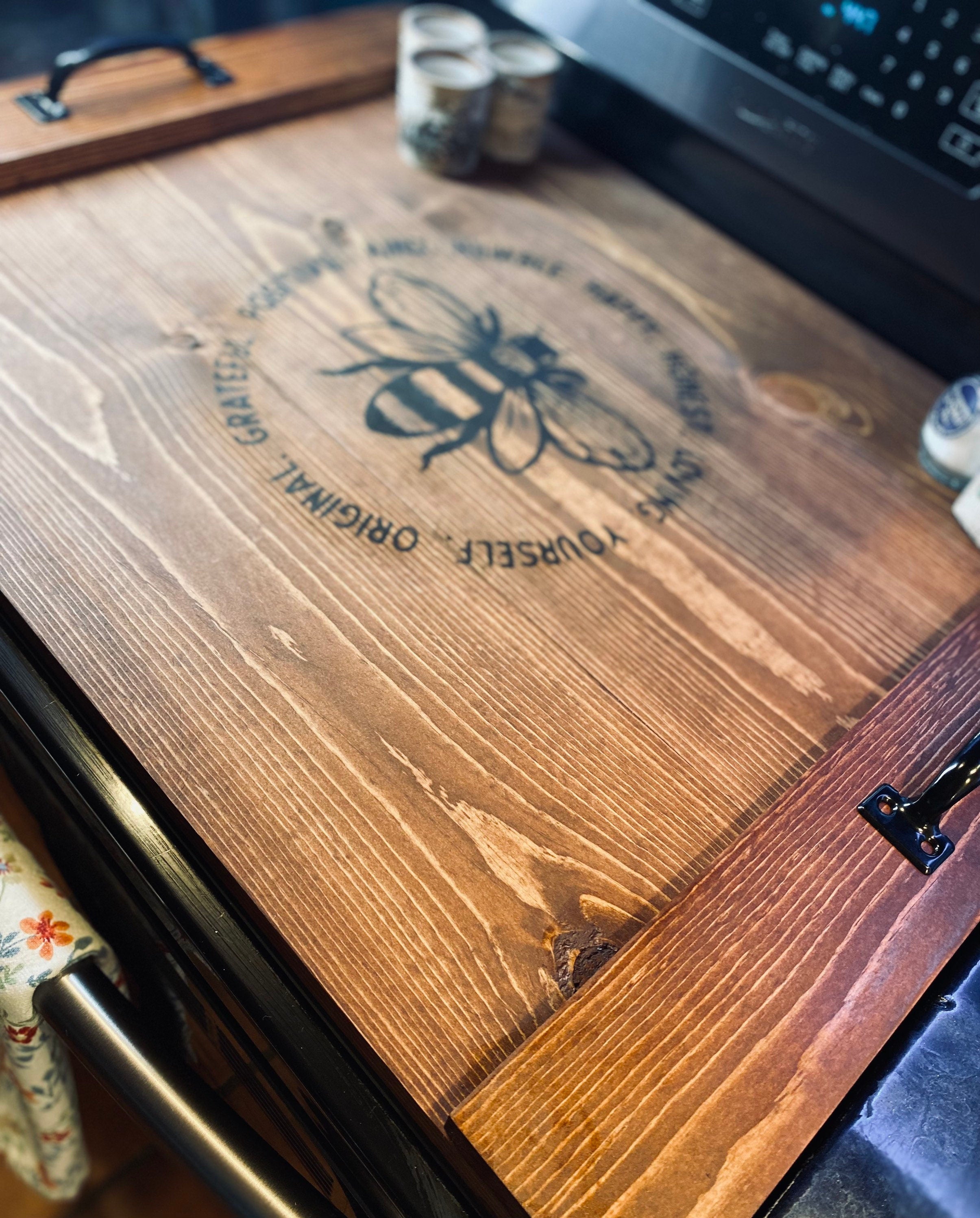 Handmade wooden stove cover in dark chestnut stain, designed for flat top electric stoves, featuring black metal handles.