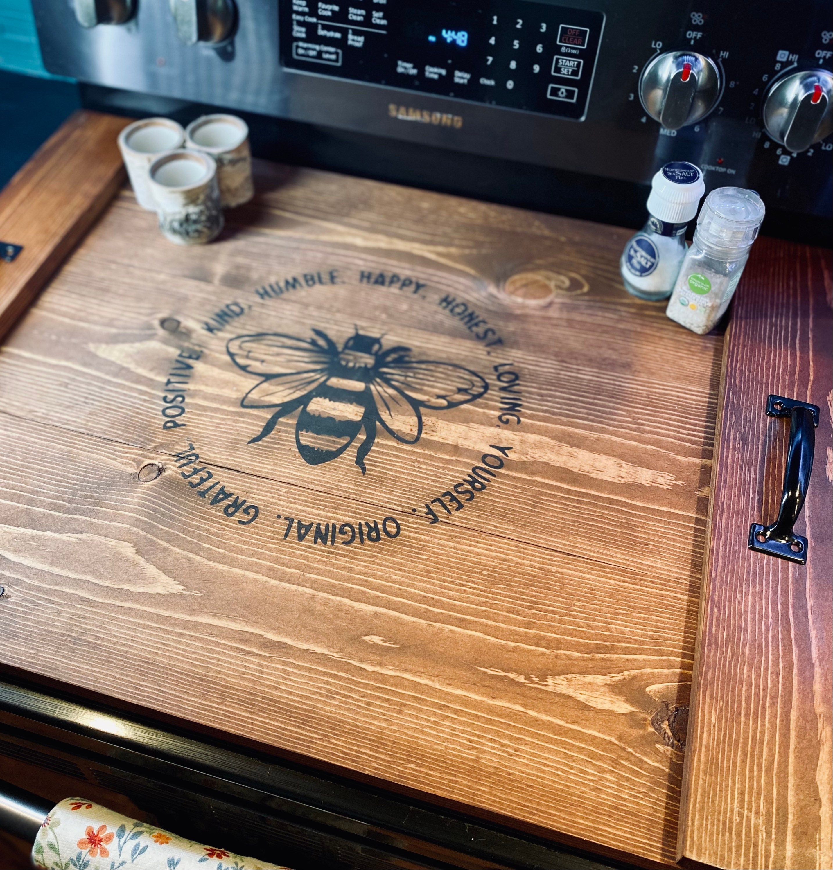 Handmade wooden stove cover in dark chestnut stain, designed for flat top electric stoves, featuring black metal handles.