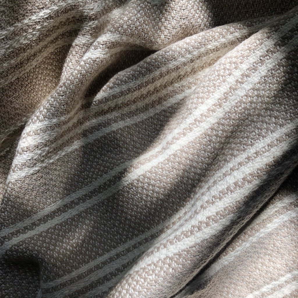 A cozy Woven Stripe Turkish Throw featuring intricate stripe patterns and hand-knotted fringe, perfect for home decor.