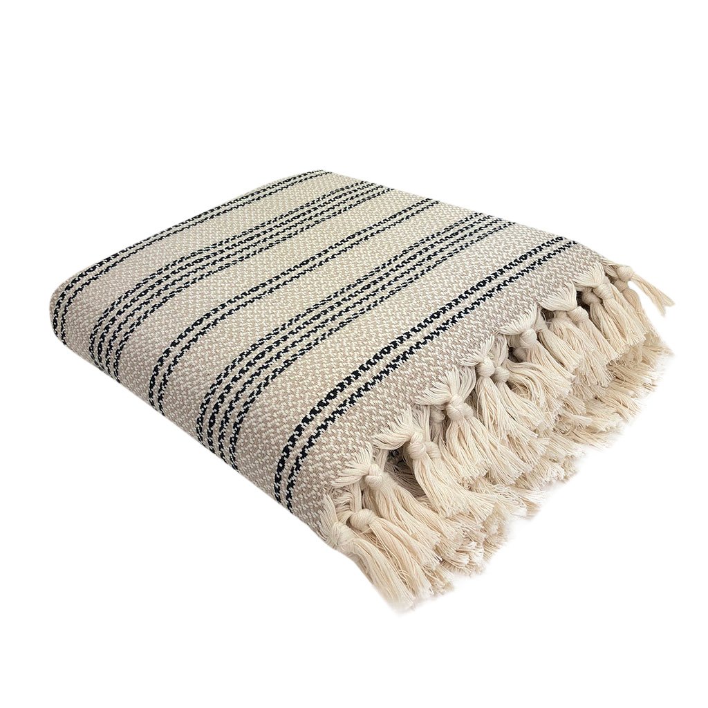 A cozy Woven Stripe Turkish Throw featuring intricate stripe patterns and hand-knotted fringe, perfect for home decor.