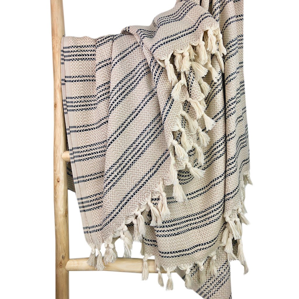 A cozy Woven Stripe Turkish Throw featuring intricate stripe patterns and hand-knotted fringe, perfect for home decor.