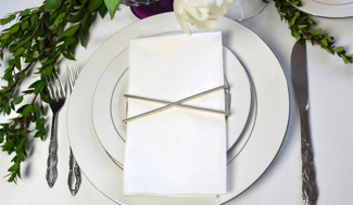 X Wrap - Shiny Silver napkin rings elegantly displayed on a dining table, showcasing their modern design and shiny finish.