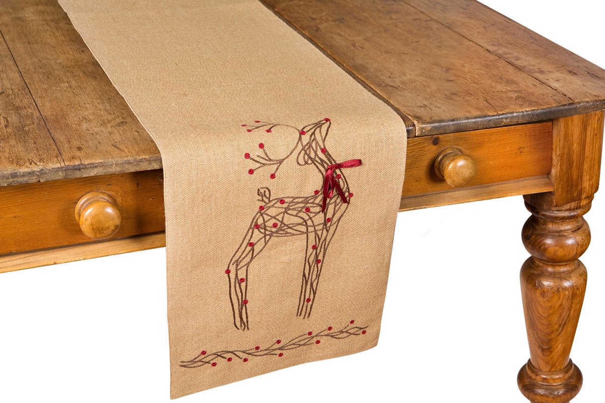 XD15814 Rustic Reindeer Jute Table Runner featuring intricate embroidery of reindeer and holly on a burlap background with a red ribbon accent.