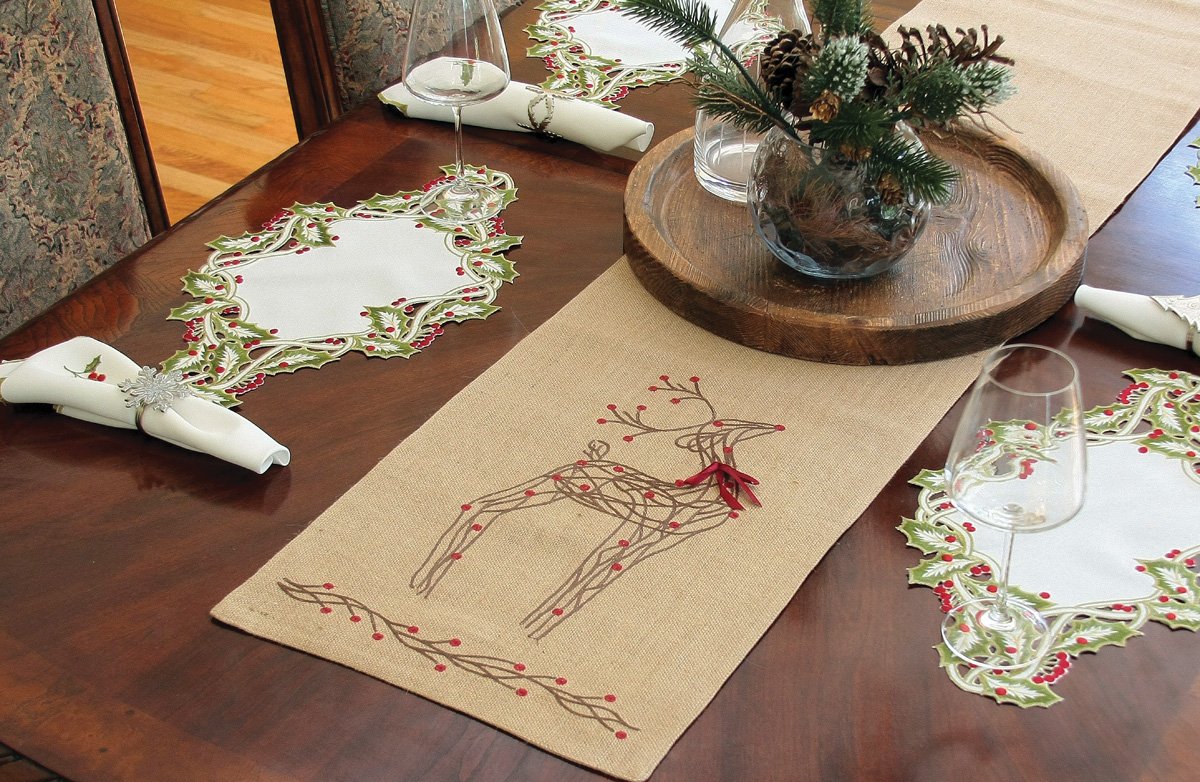 XD15814 Rustic Reindeer Jute Table Runner featuring intricate embroidery of reindeer and holly on a burlap background with a red ribbon accent.