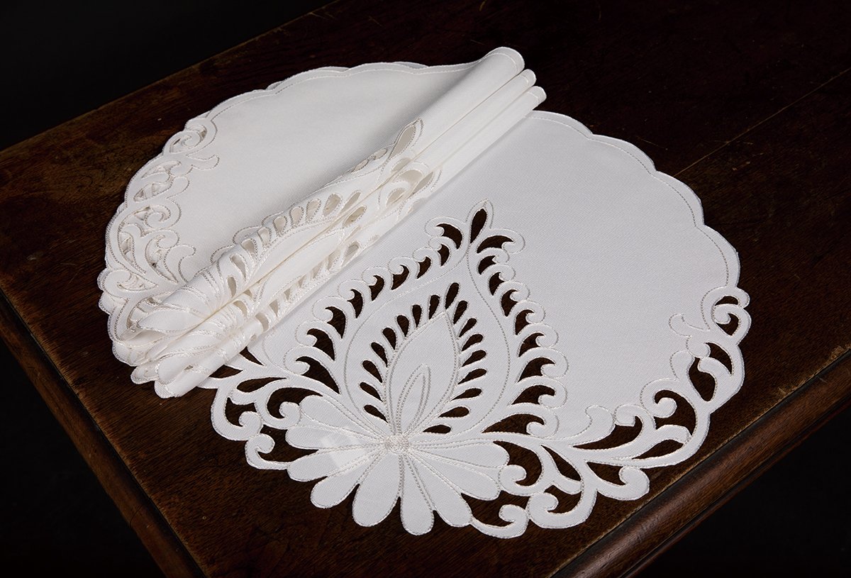 Set of 4 XD17144 Wilshire Placemats with scalloped cutwork edges and floral embroidery on a textured beige background.