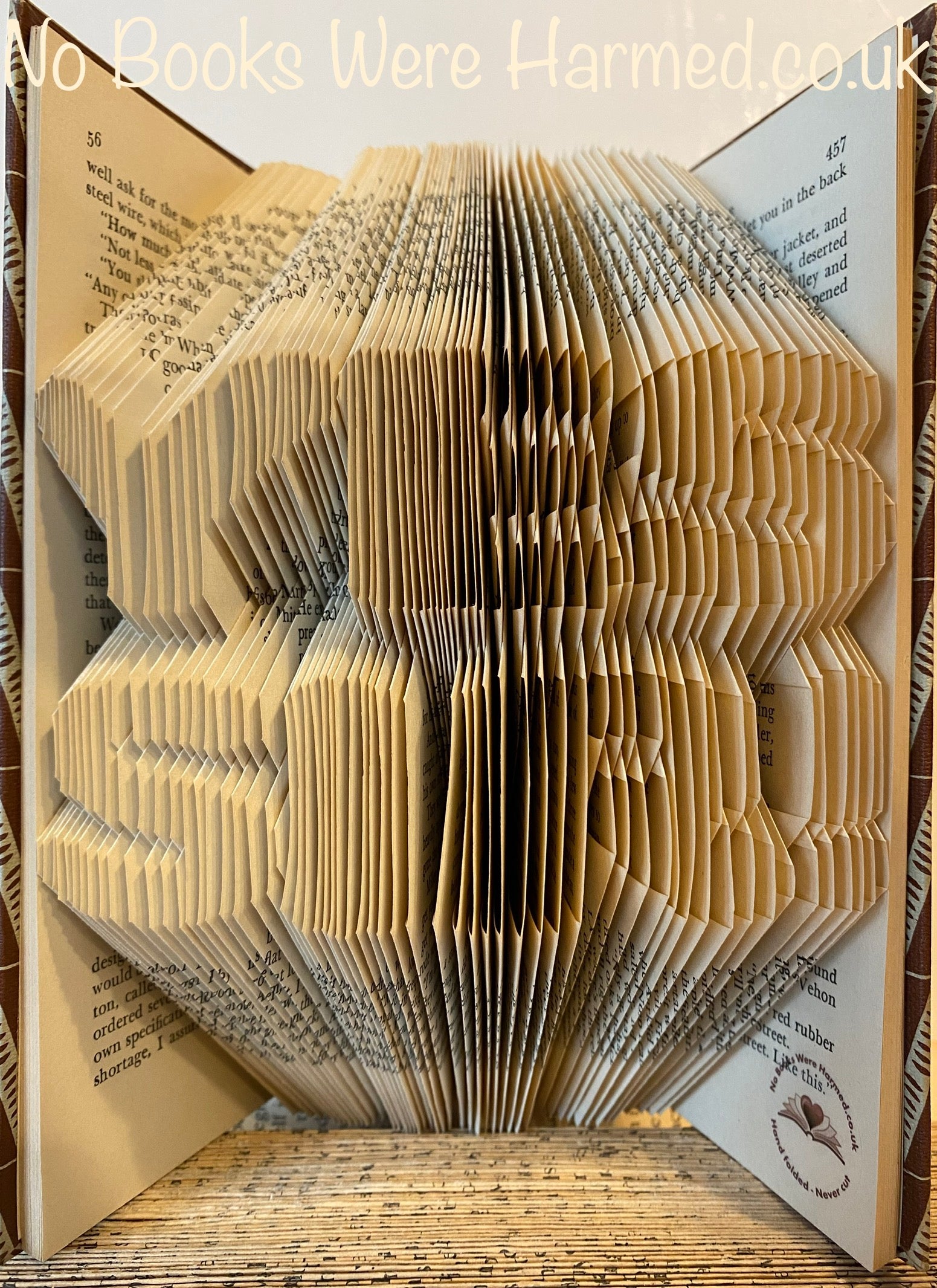 A unique piece of hand-folded book art from YES SIR!, showcasing intricate folds and vintage book pages in a creative design.