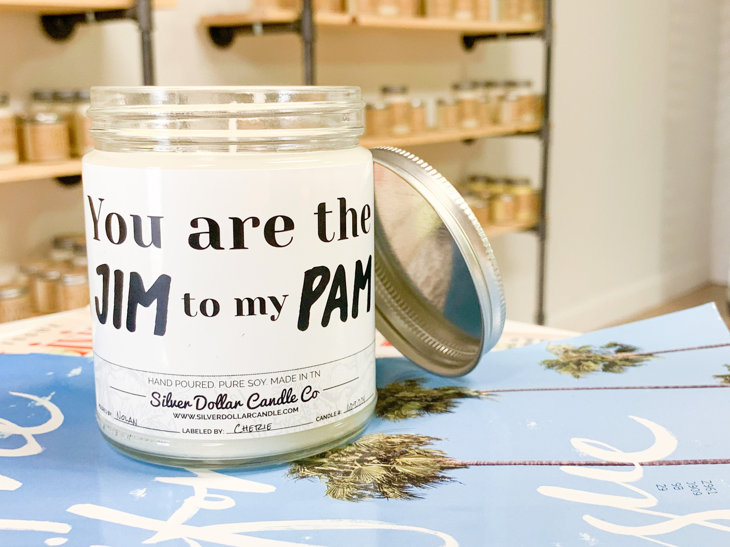 A beautifully designed candle labeled 'You Are The Jim to my Pam', showcasing its romantic theme and available scents.