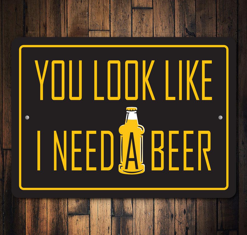 You Look Like I Need a Beer Sign made of high-quality aluminum, featuring humorous text, ideal for home bars and man caves.