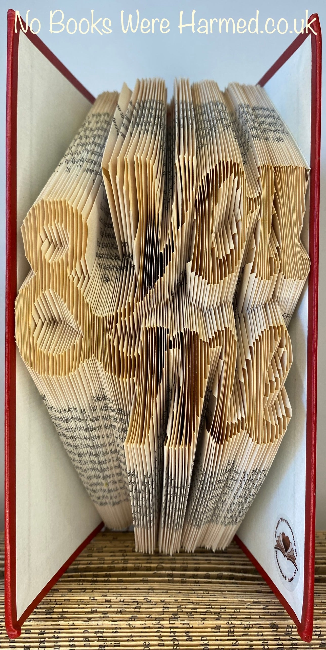 A unique piece of handcrafted book art made from vintage books, showcasing intricate hand-folded pages in various colors.