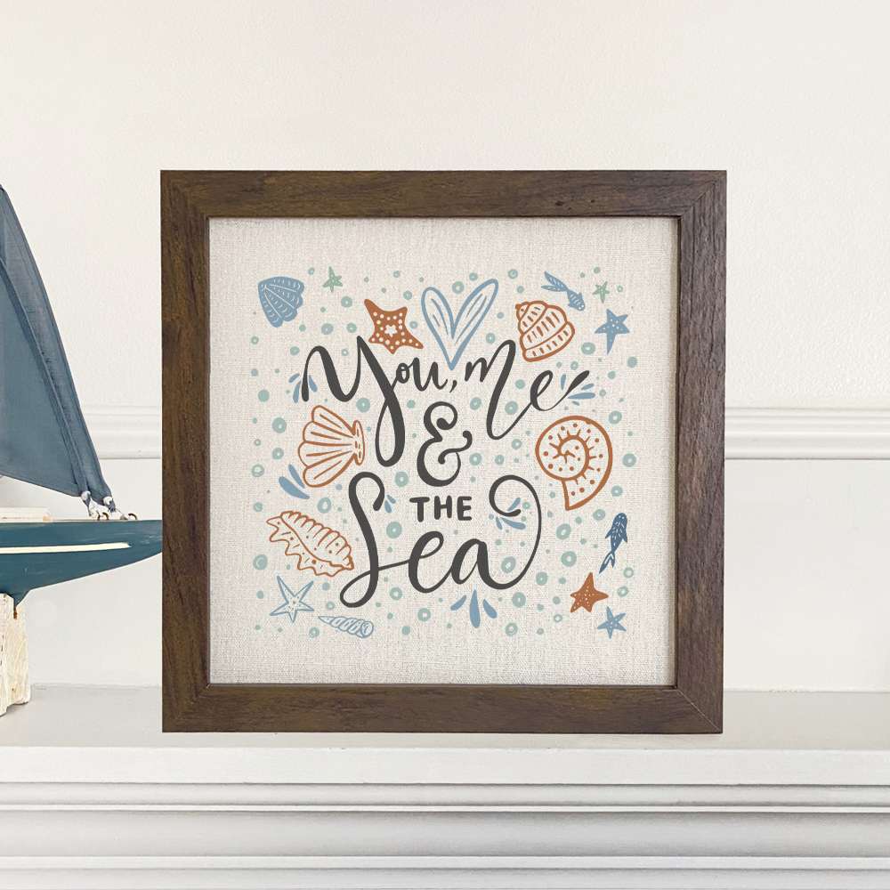 You Me and the Sea Framed Sign featuring a stylized wood frame with a linen-look background, perfect for coastal decor.