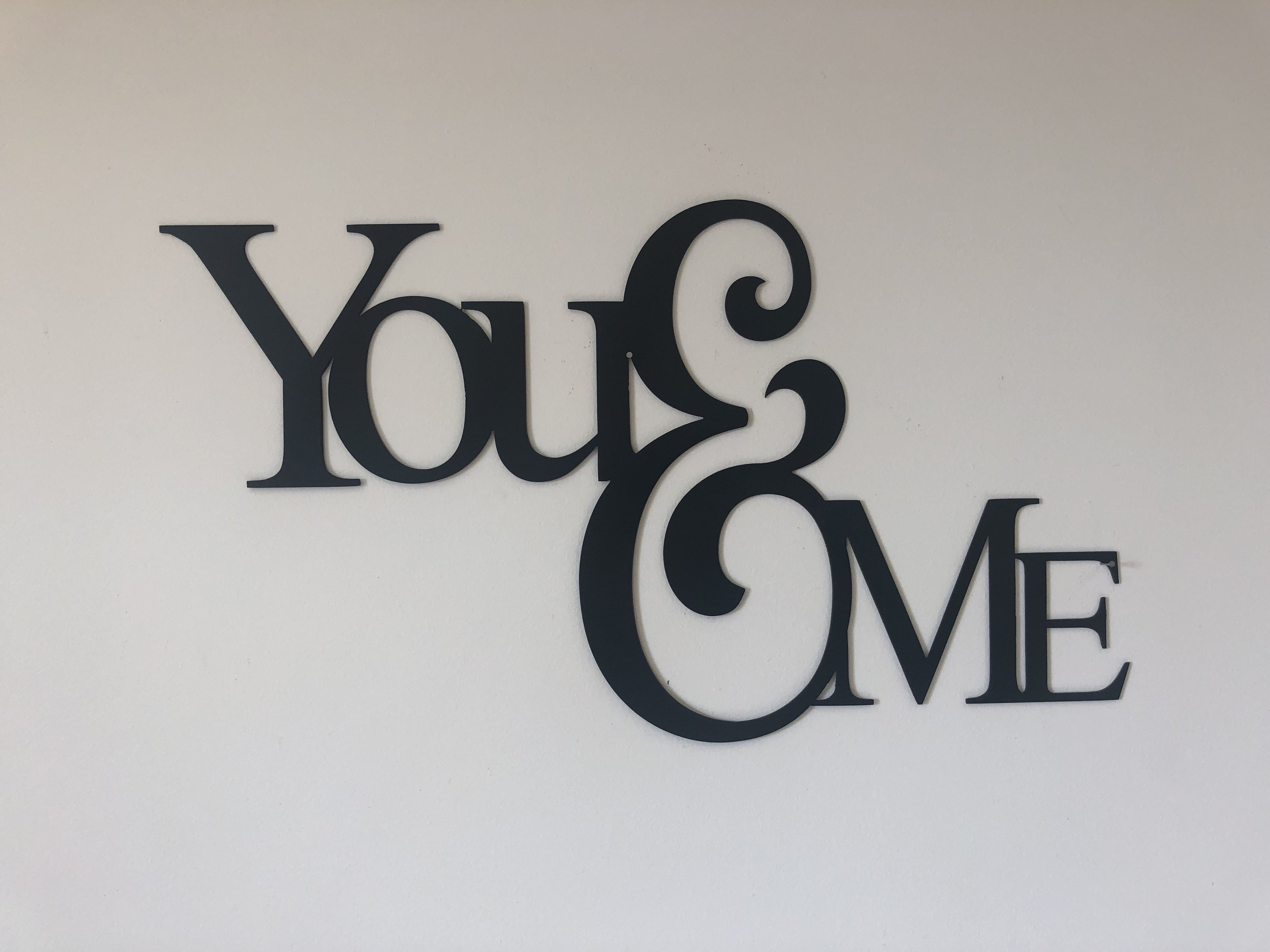 You & Me Metal Wall Art in low gloss black finish, measuring 25 inches wide and 14 inches tall, showcasing a modern design perfect for home decor.