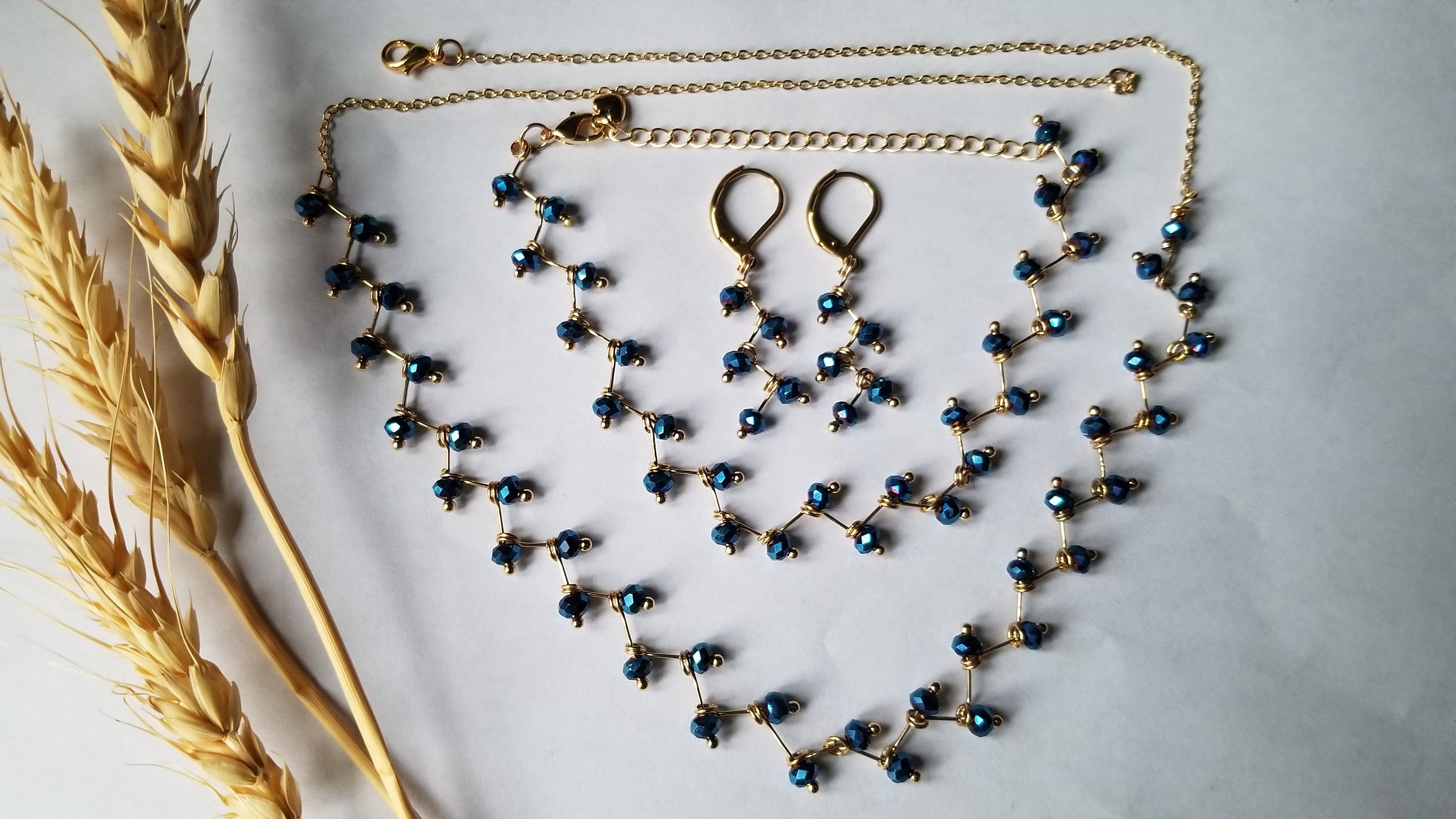 Zig Zag Blue Jewelry Set featuring a chain, bracelet, and earrings with shining blue beads and gold plating.