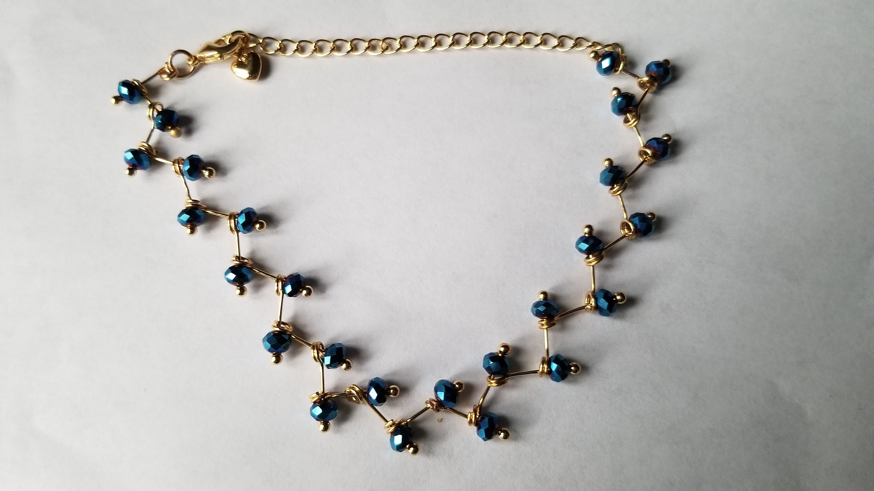 Zig Zag Blue Jewelry Set featuring a chain, bracelet, and earrings with shining blue beads and gold plating.