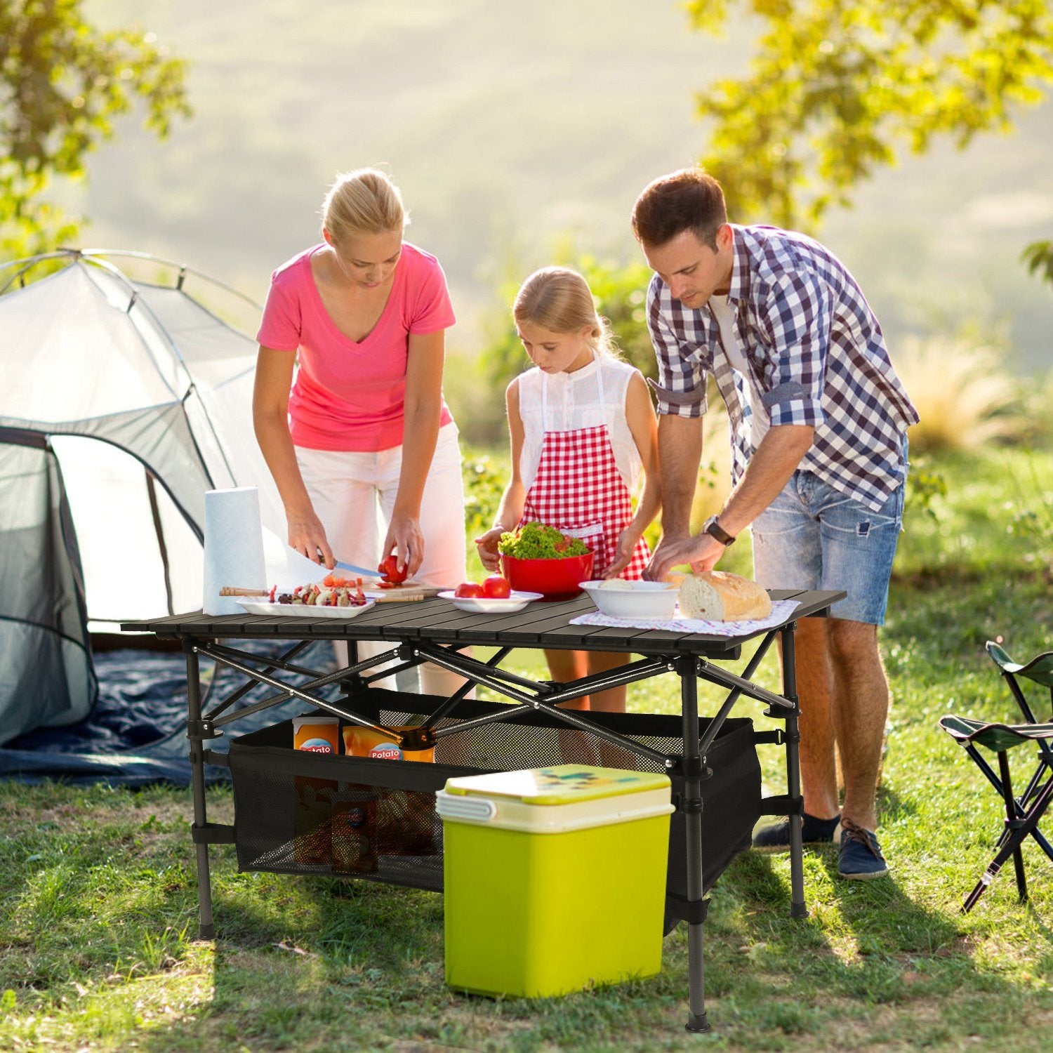 Lightweight aluminum folding camping table set up outdoors with a mesh storage basket underneath.