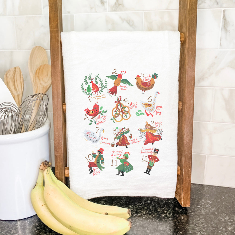 A vibrant cotton tea towel featuring a festive 12 Days of Christmas design, perfect for holiday kitchen use.