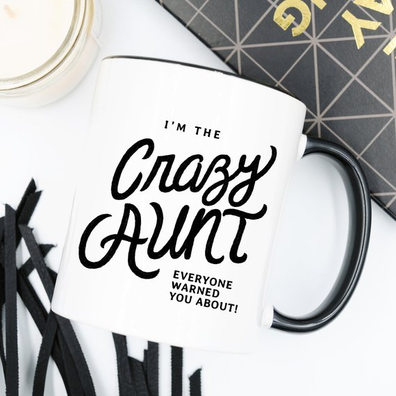 A humorous 11oz coffee mug featuring the phrase 'I'm The Crazy Aunt Everyone Warned You About' in bold letters, perfect for gifting.