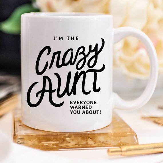 A humorous 11oz coffee mug featuring the phrase 'I'm The Crazy Aunt Everyone Warned You About' in bold letters, perfect for gifting.