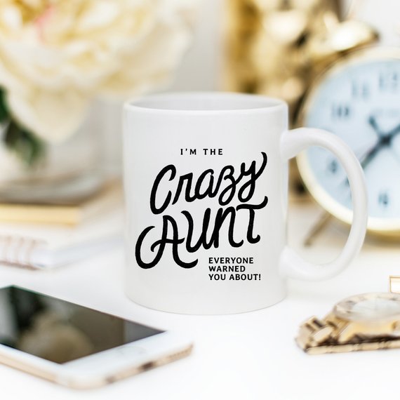 A humorous 11oz coffee mug featuring the phrase 'I'm The Crazy Aunt Everyone Warned You About' in bold letters, perfect for gifting.