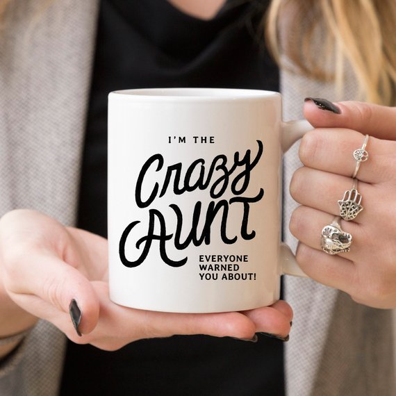 A humorous 11oz coffee mug featuring the phrase 'I'm The Crazy Aunt Everyone Warned You About' in bold letters, perfect for gifting.