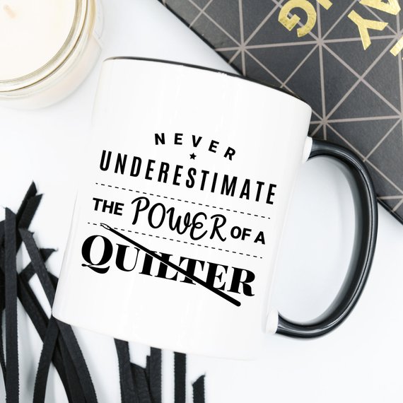 A humorous 11oz coffee mug featuring the quote 'Never Underestimate The Power Of A Quilter', crafted from high-quality ceramic.