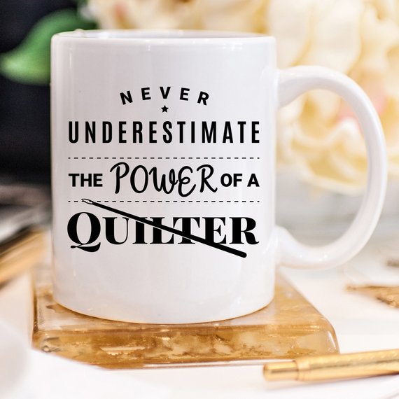 A humorous 11oz coffee mug featuring the quote 'Never Underestimate The Power Of A Quilter', crafted from high-quality ceramic.